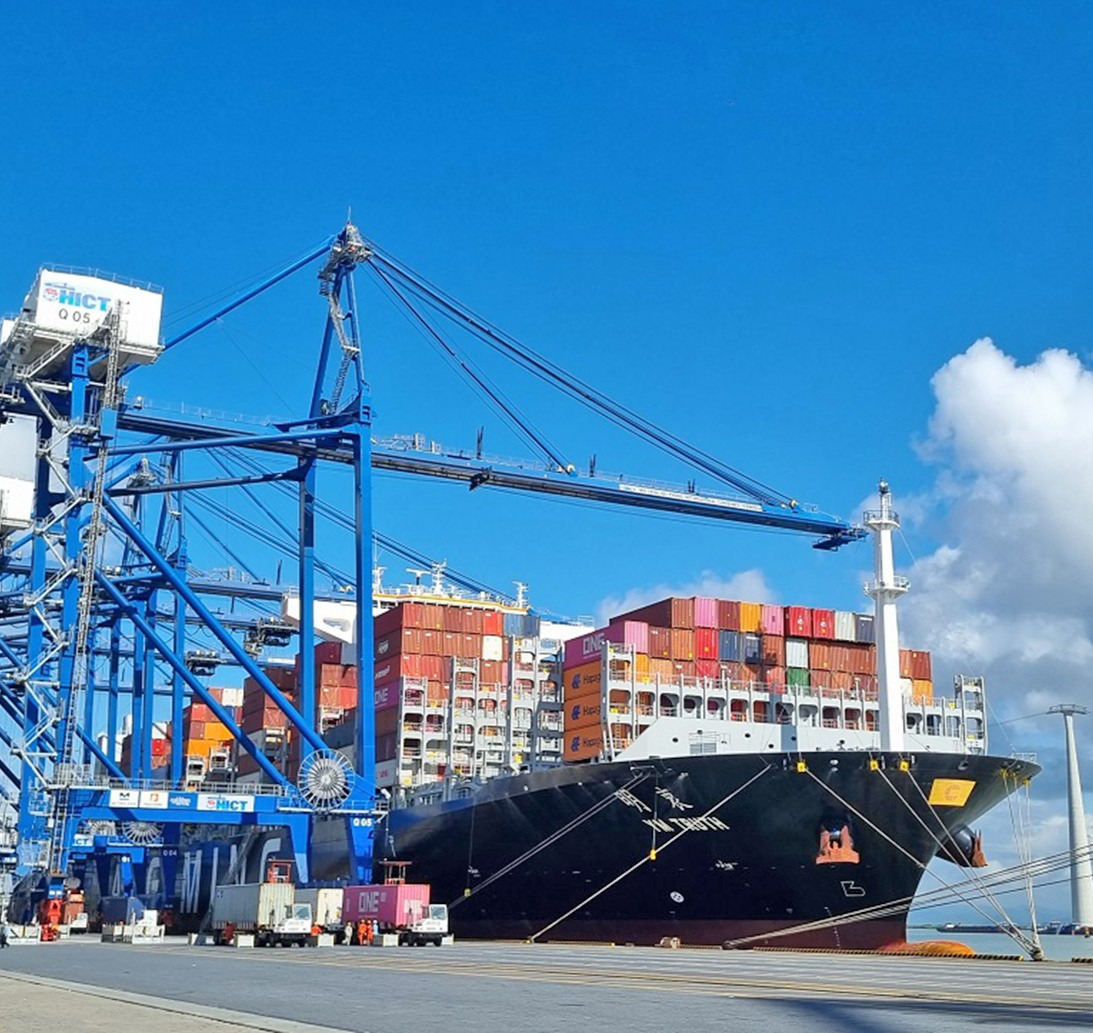 Colorful containers and freight trucks at a shipping dock under a sunset sky